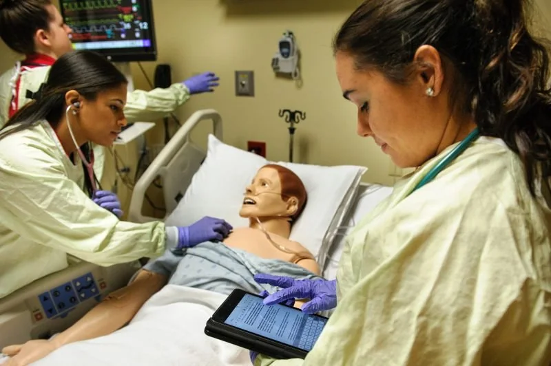 Nursing student in scrubs using a tablet